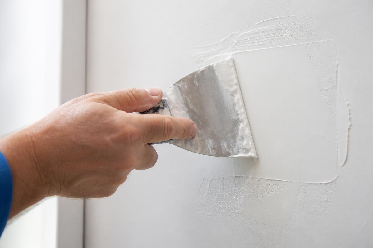 Handyman patching drywall with joint compound in a Las Vegas home